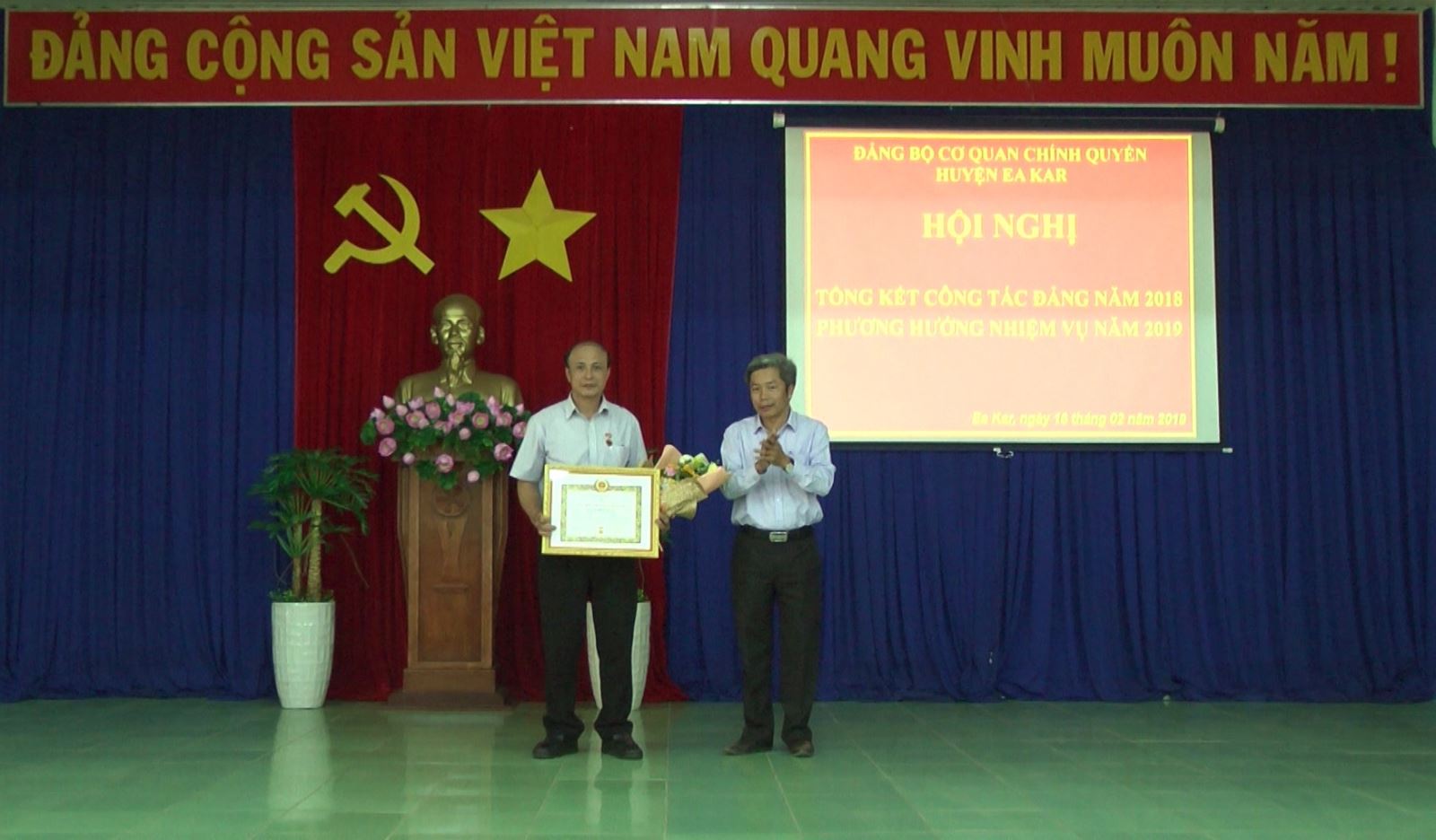 Đồng chí Nguyễn Văn Hà – Phó Bí thư huyện ủy, Chủ tịch UBND huyện, Bí thư Đảng bộ cơ quan chính quyền huyện EaKar trao huy hiệu 30 năm tuổi Đảng cho đồng chí Nguyễn Đình Thặng – Phó Bí thư chi bộ Y tế Dân số